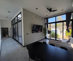 a living room with a ceiling fan and a table at Noir Blanc Modern Villa in Ko Phangan