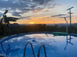 a large swimming pool with a sunset in the background at Habitaciones cama doble in La Vega