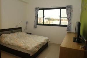 1 dormitorio con cama y ventana en 逸遊蔚境民宿, en Magong