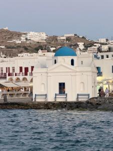 a white building with a blue dome next to the water at Chora Suite in Mikonos