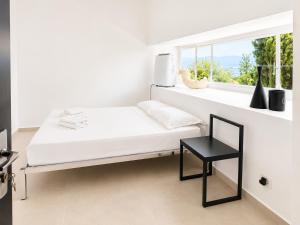 a white bedroom with a white bed and a black chair at ÉLÉGANT STUDIO et PARKING DANS BATIMENT HISTORIQUE in Saint-Tropez