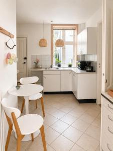 a kitchen with white cabinets and a table and chairs at Lejlighed midt i Thisted in Thisted