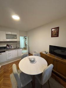ein Wohnzimmer mit einem Tisch und einer Küche in der Unterkunft Stan Stefi in Pljevlja