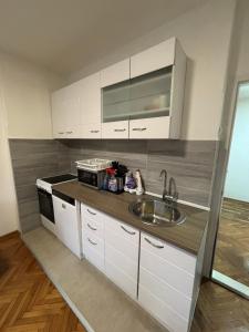 Eine Küche mit weißen Schränken, Spüle und Mikrowelle in der Unterkunft Stan Stefi in Pljevlja