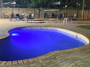 a blue swimming pool with a table and chairs at Rugira Guest House in Vosburg