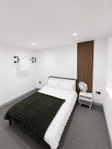 a white bedroom with a bed and a chair at AS Residences in Preston