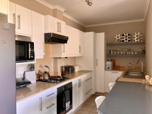 a kitchen with white cabinets and a counter top at Beautiful 3 bedroom flat in Grahamstown