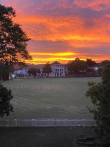 a sunset over a large field in front of a building at Beautiful 3 bedroom flat in Grahamstown