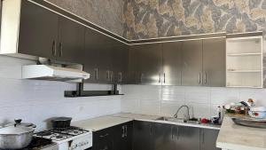 a kitchen with gray cabinets and a stove and sink at Mezbon in Termiz