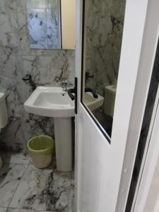 a white bathroom with a sink and a mirror at Casa T2 in Matola