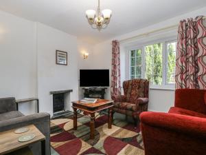 a living room with a couch and a table and a tv at Fountain Cottage in Keswick