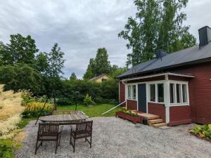 a small house with a table and chairs in front of it at Tunnelmallinen kaksio järven lähellä, vuokraajalle käytössä myös kajakkikaksikko in Heinola