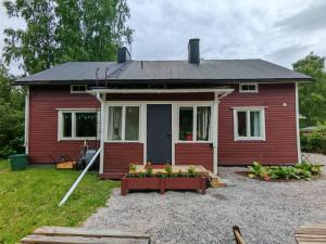 a red house with a table in front of it at Tunnelmallinen kaksio järven lähellä, vuokraajalle käytössä myös kajakkikaksikko in Heinola +8 photos