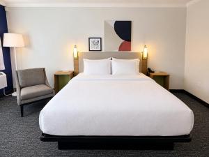 a bedroom with a large white bed and a chair at Spark By Hilton Lake George Outlets in Lake George