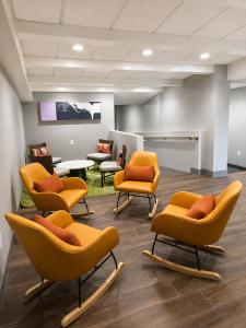 a waiting room with orange chairs and a table at Spark By Hilton Lake George Outlets in Lake George