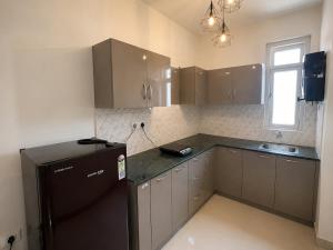 a kitchen with a black refrigerator and a window at Cinema Experience -Premium Studio in Karnal