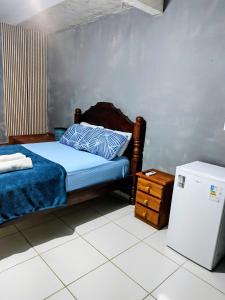 a bedroom with a bed and a small refrigerator at suíte feliz in Belém