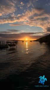 a sunset on a beach with a boat in the water at Tiare and Turtle in Bora Bora