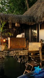 a house with a thatched roof with a bed and chairs at Tiare and Turtle in Bora Bora