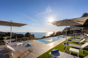 a pool with chairs and umbrellas next to the ocean at Dimora Maiuri L'Olivella in Anacapri