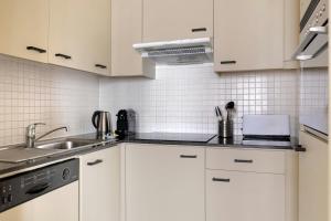 a kitchen with white cabinets and a sink at Marriott Executive Apartments Brussels in Brussels