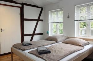two beds in a bedroom with two windows at Altes Rauchhaus in Ebstorf