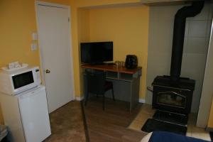 a room with a stove and a desk with a microwave at Motel des Pentes et Suites in Saint-Sauveur-des-Monts