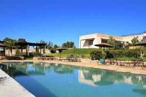 a swimming pool with tables and chairs and umbrellas at Tassourt Lodge in Essaouira