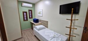 a small room with a bed and a flat screen tv at Hotel Orleans in Petrópolis