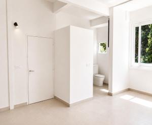 a white bathroom with a toilet and a window at ÉLÉGANT STUDIO et PARKING DANS BATIMENT HISTORIQUE in Saint-Tropez