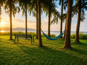 a bench with a hammock in a park with palm trees at Eben Lake Kivu cottages and Villas in Kagano +16 photos