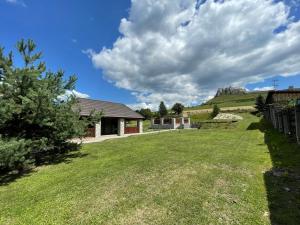 a yard with a house and a hill in the background at Pension Chalupka l with a panoramic view of Spiš Castle in Spišské Podhradie