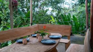 a wooden table with plates and dishes on a porch at El Cerrito in Puerto Jiménez