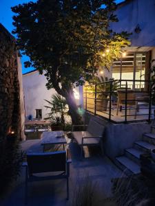 a patio with a tree and some tables and benches at Maison Ancienne Minervois in La Caunette