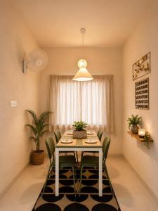 a dining room table with green chairs and a light fixture at Luxurious boho pool villa nandi hills in Bangalore +9 photos