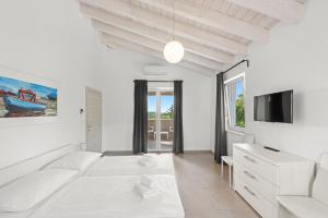 a white bedroom with a bed and a tv at Villas Marisol in Premantura