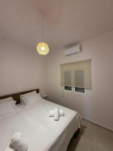 a white bedroom with a bed with two towels on it at Aigialos Villas with Private Beach by Hospi Living in Ferma