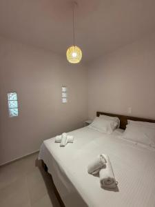 a bedroom with a bed with towels on it at Aigialos Villas with Private Beach by Hospi Living in Ferma