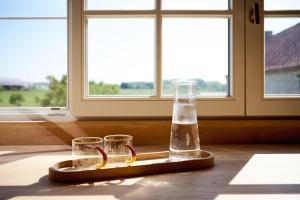 a tray with two glasses and a bottle on a table at De Volle Maan - Lentehuis in Sint-Lievens-Houtem