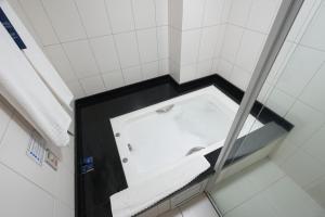 a bath tub in a bathroom with white tiles at Firenze Business Hotel in Palhoça +74 photos