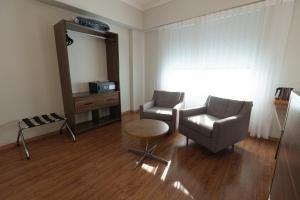 a living room with a chair and a table at Firenze Business Hotel in Palhoça