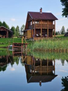 a log cabin on a lake with its reflection in the water at Guest house Oaze in Miglāni