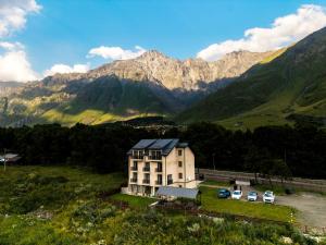 a house in a field with mountains in the background at Hotel Gold Kazbegi in Kazbegi