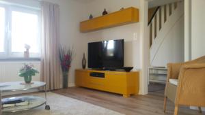 a living room with a television on a yellow cabinet at Direkter Blick auf´s Wasser in Fahrdorf