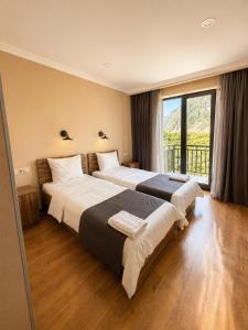two beds in a hotel room with a large window at Hotel Gold Kazbegi in Kazbegi