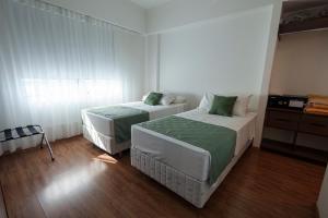 two beds in a small room with wood floors at Firenze Business Hotel in Palhoça