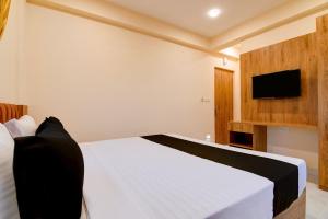a bedroom with a white bed and a flat screen tv at Hotel O NamaStay in kolkata