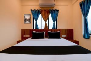 a bedroom with a large bed with blue curtains at Hotel O NamaStay in kolkata