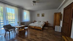 a bedroom with a bed and a table and chairs at Pensjonat Fluder in Jaszczurowa