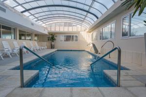 una piscina con techo de cristal y sillas en Sul Mare Hotel en Valeria del Mar